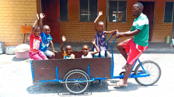 The children take a ride in the box of the cargo bike.